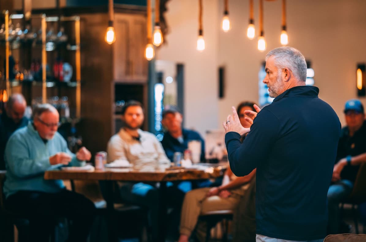 A member speaking to a seated group at the clubhouse bar